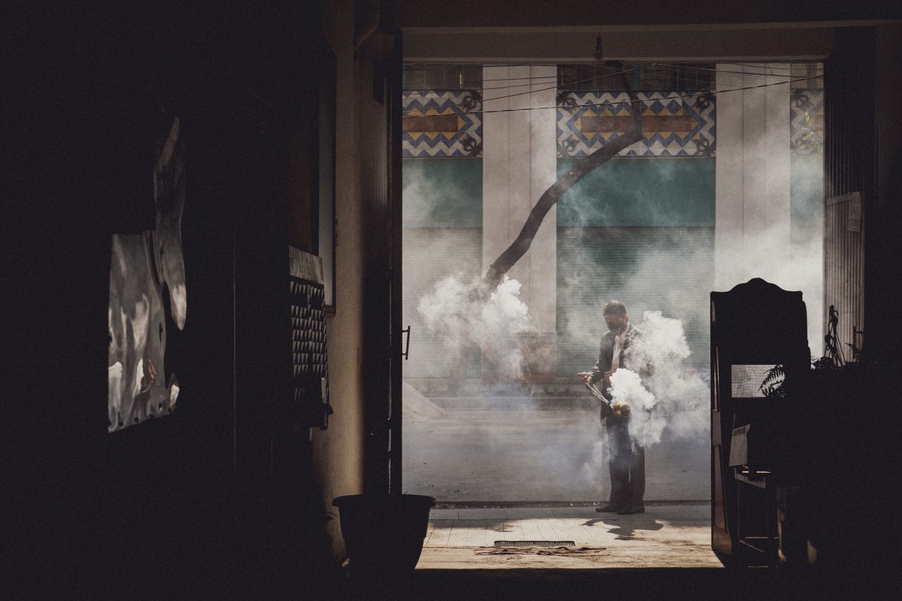 muž s rouškou zahalený kouřem z kadidla, Mexico